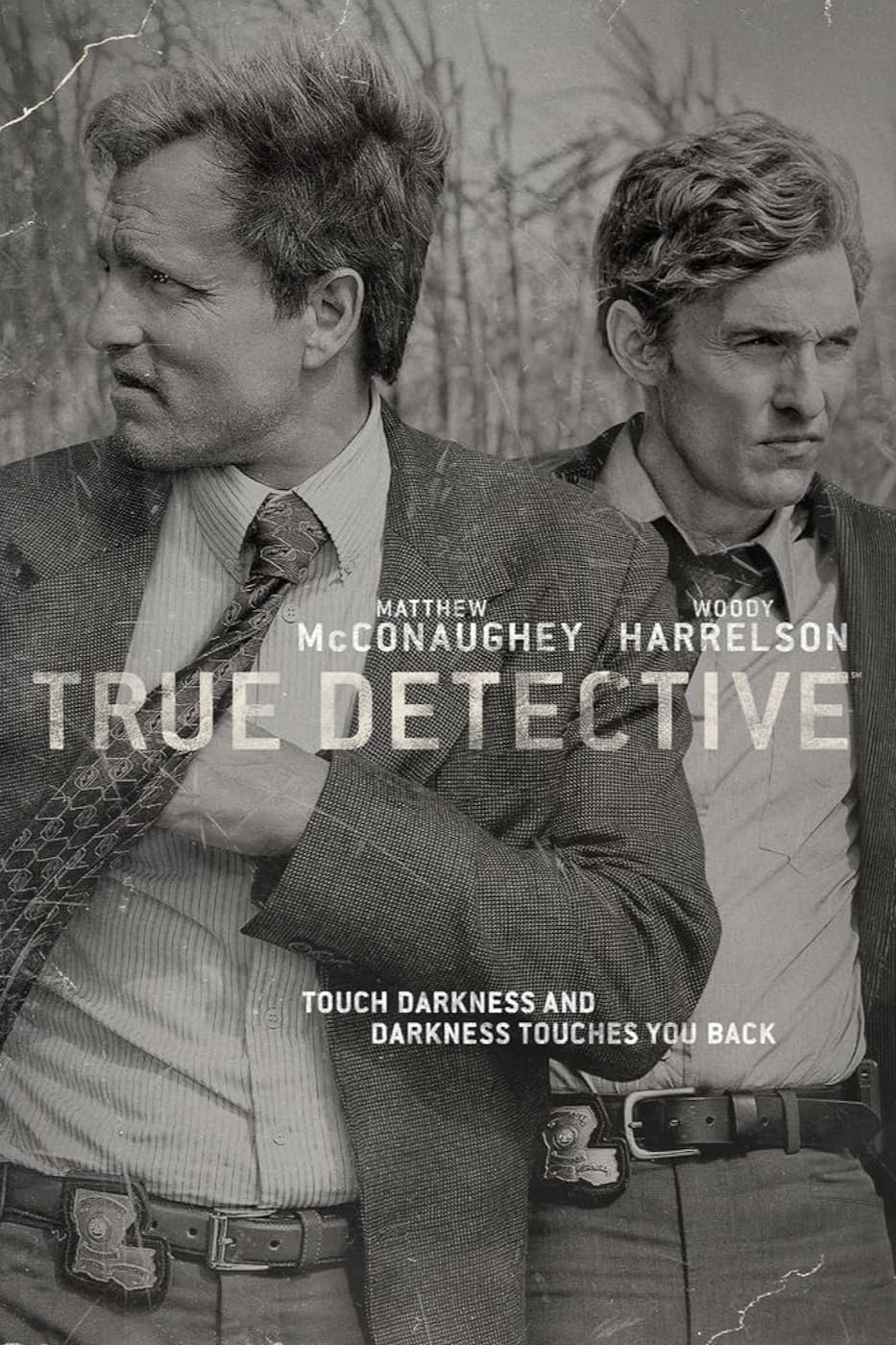 Black-and-white poster of True Detective features two men in suits—one adjusting his tie, the other beside him. With actors' names, title, and the tagline: Touch darkness and darkness touches you back. Also available via IPTV Latino.