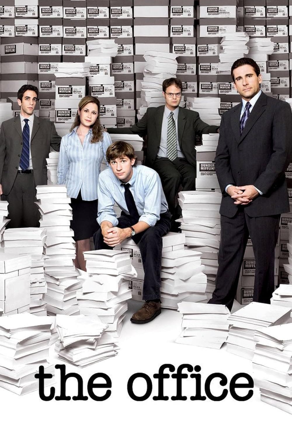 Five people in office attire stand and sit among large stacks of paper and boxes labeled Dunder Mifflin Paper Company, with the words "the office" below them, evoking a classic scene now enjoyed by IPTV Latino viewers.